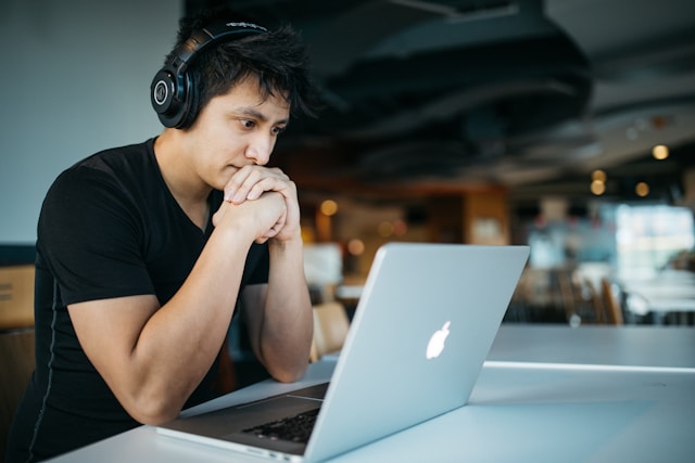 covek sedi za stolom ispred laptopa